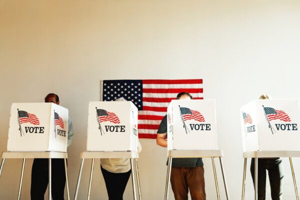 US election day, Diverse people at voting booth at US election station with American flag in background. Diverse people in line to vote at US election day. Vote for American democracy