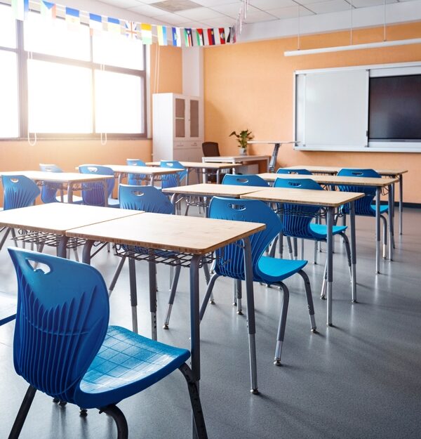 Empty school classroom with chairs and desks, a tv on the whiteboard, and orange walls
