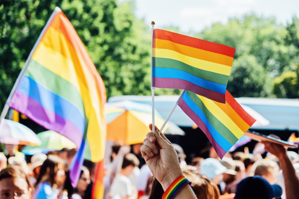 People are waving pride flags at an LGBTQ+ event.