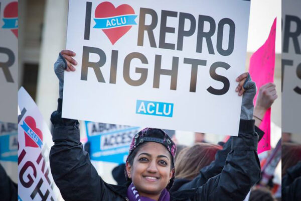Person holding protest sign that says I (heart) REPRO RIGHTS and ACLU logo