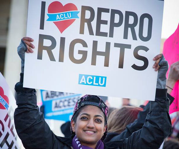 Person holding protest sign that says I (heart) REPRO RIGHTS and ACLU logo