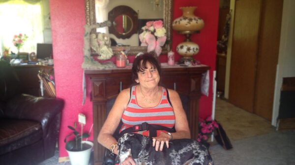 Lawsuit plaintiff Christie Mathwig sitting in a wheel chair with her dog on her lap in her house