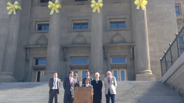 Podium on Idaho state capitol steps with people standing behind speaker at podium