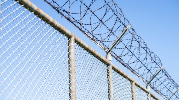 Large fence with barb wire at the top, often seen surrounding prisons.
