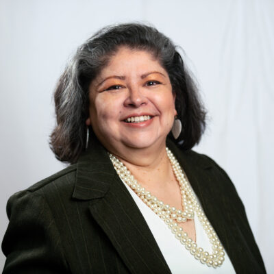 Dina is centered in front of a white cloth background.