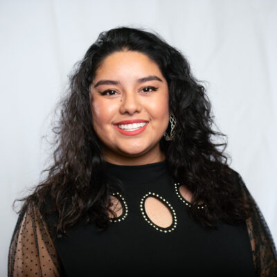 Rosseli is centered in front of a white cloth background.