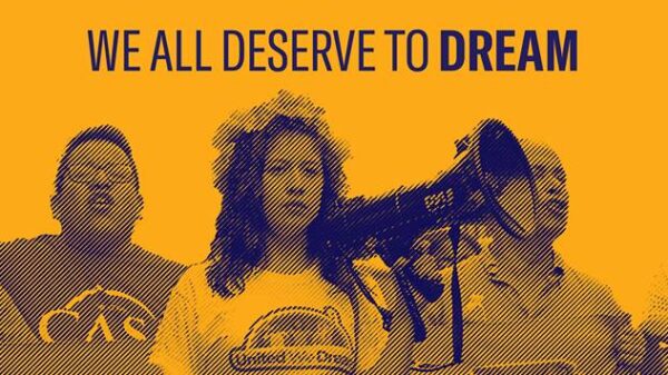 A Yellow rectangle has the words "we all deserve to dream" at the top in blue letters. There are 5 people pictured below. The person in the middle has a blowhorn in their hand, raised almost to their face.