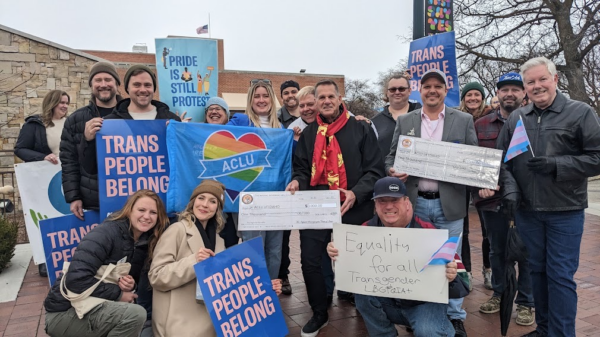 A group of people holding signs that read "trans people belong"