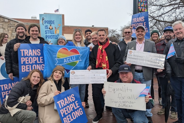 A group of people holding signs that read "trans people belong"