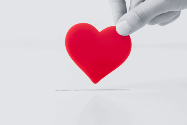 Black and white image of hand grabbing a red heart
