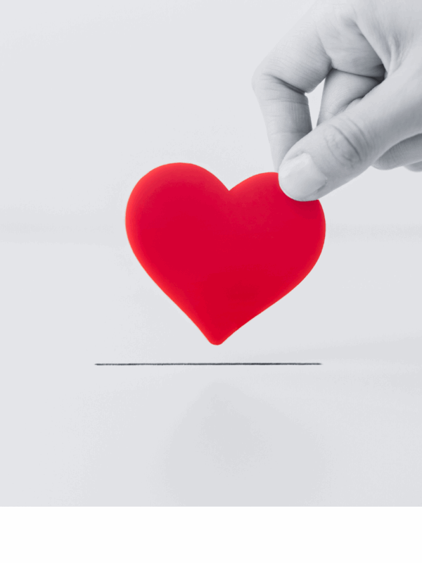 Black and white image of hand grabbing a red heart