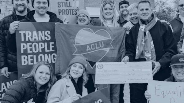 Blue tinted picture of ACLU staff holding signs that say Trans People Belong and Pride is Still Protest