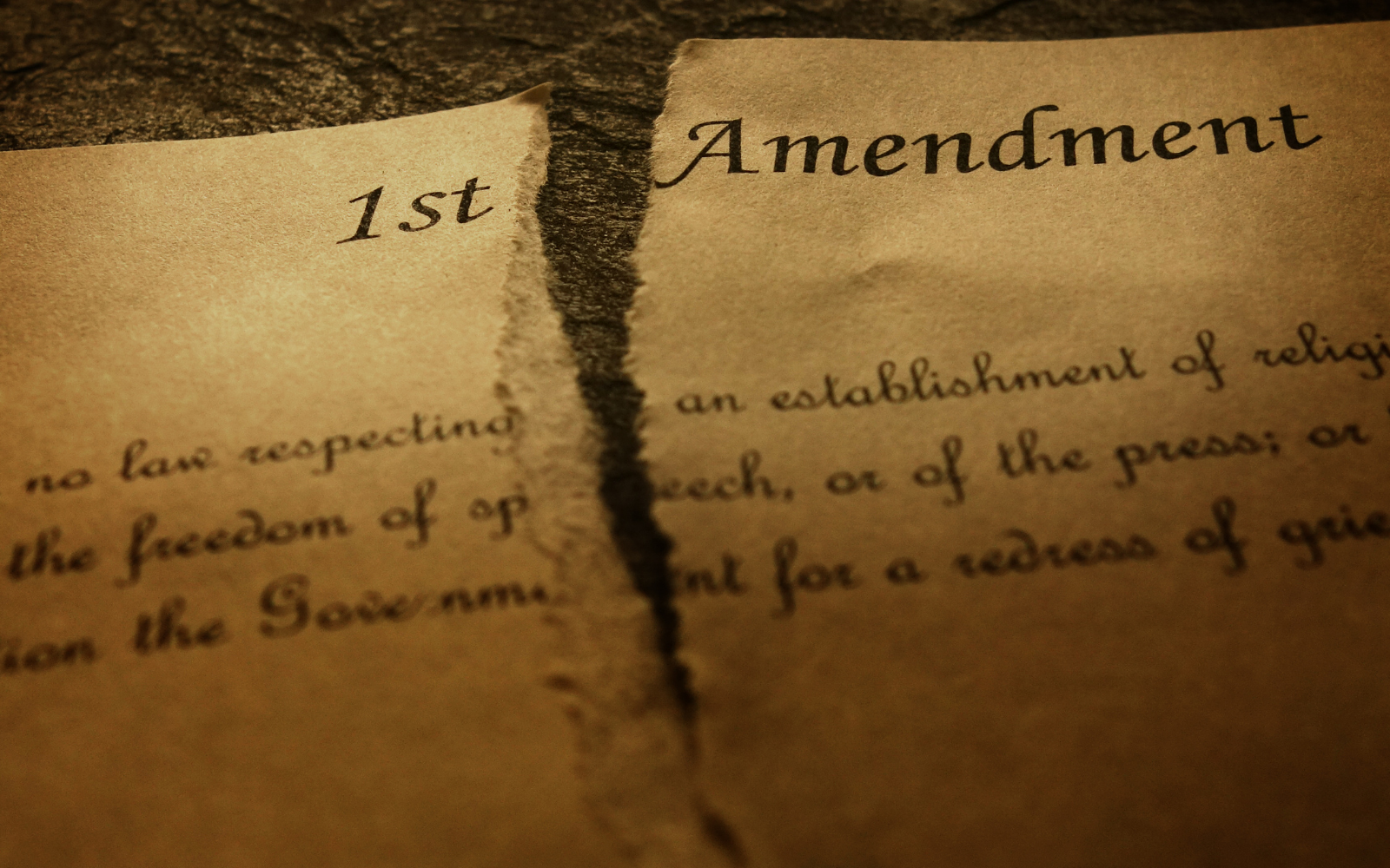 An aging document with the First Amendment is torn in half