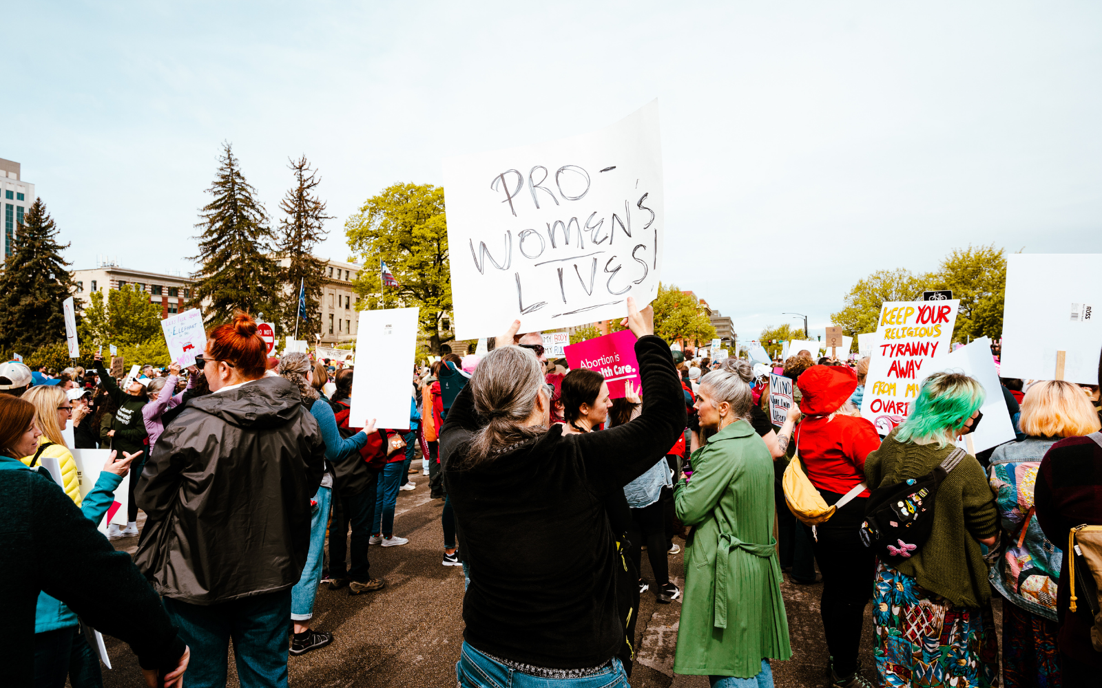 A woman at a protest holds a sign that says "pro women's lives"