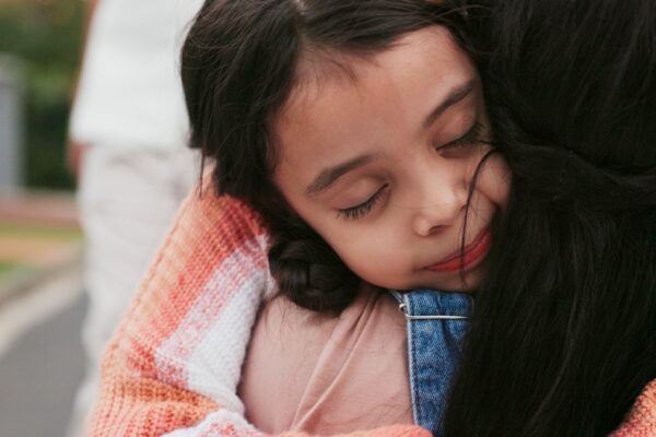 A young child hugging her mother.
