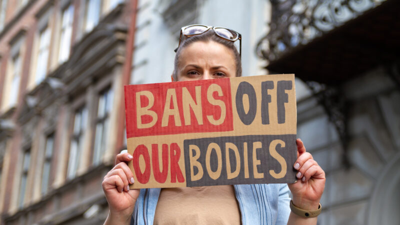 Woman holds a "bans off our bodies" sign