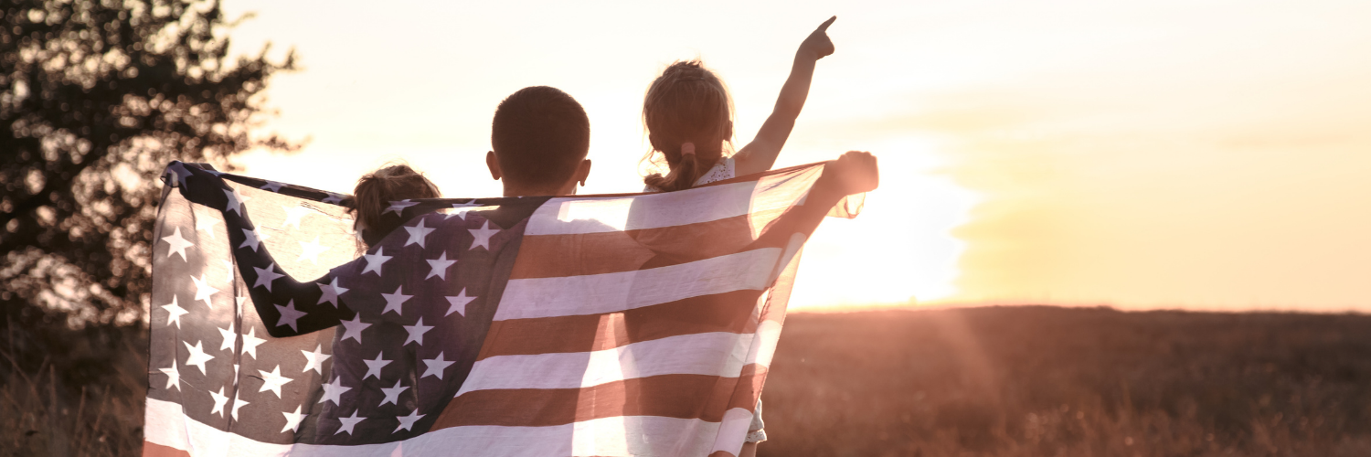 children face the sunset in a field holding an american flag