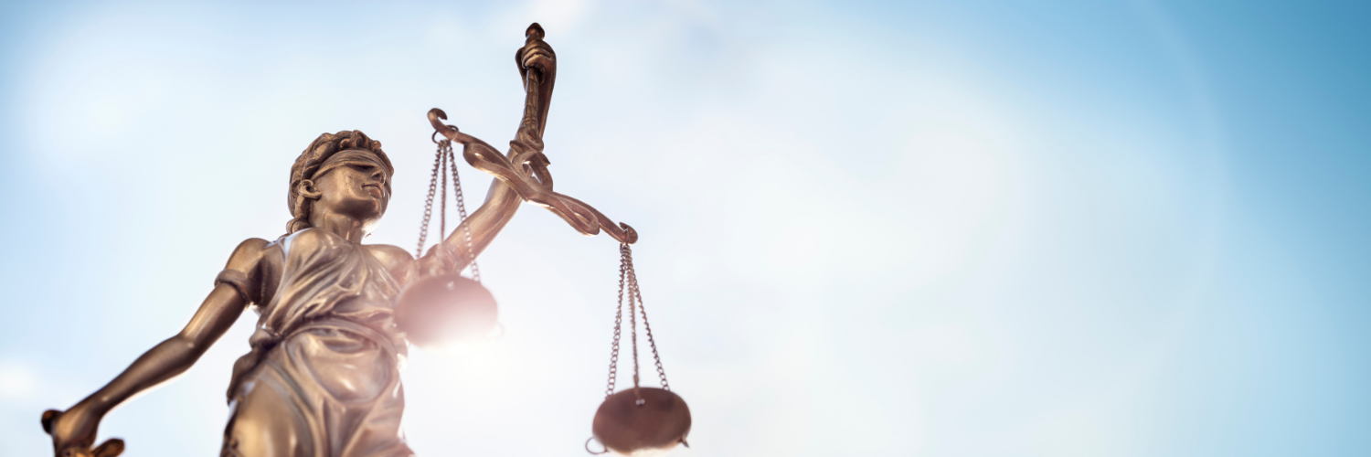 Lady Justice figurine with the sun shining in the background