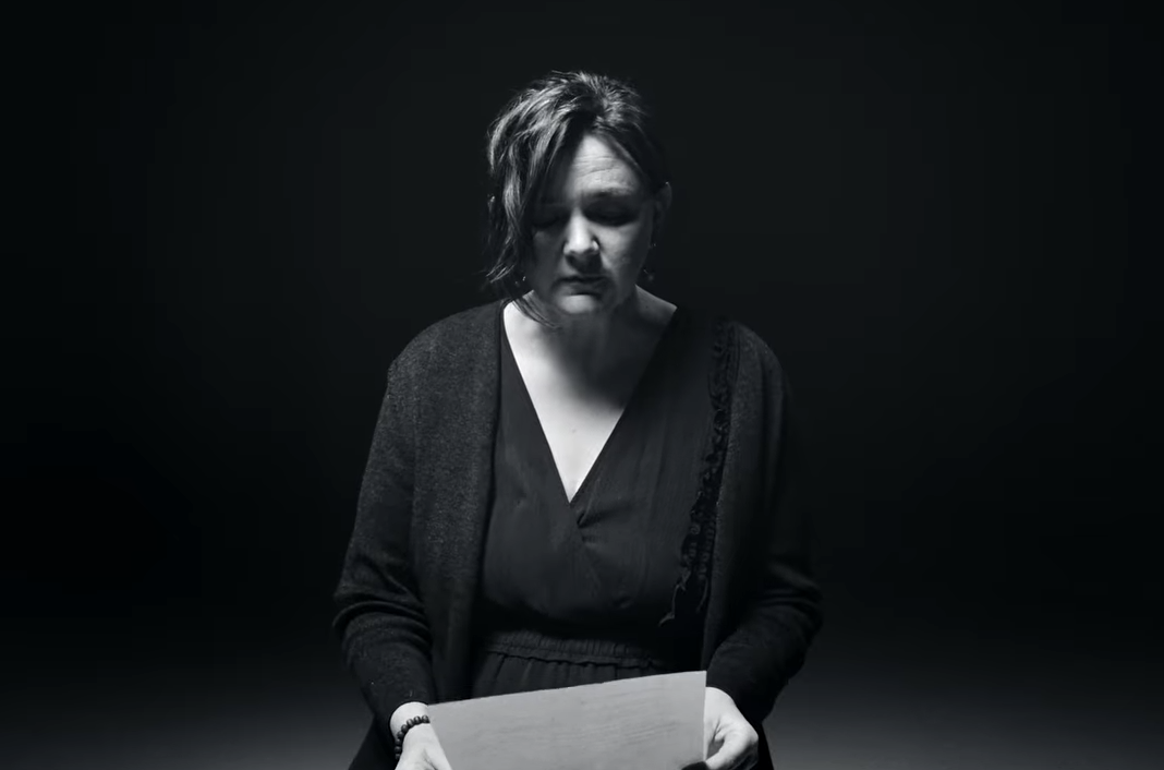 Image of a person with a black background reading a story from an immigrant affect by the Wilder raid.