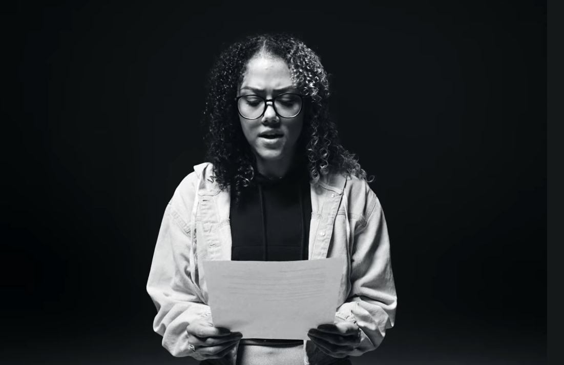 Image of a person with a black background reading a story from an immigrant affect by the Wilder raid.