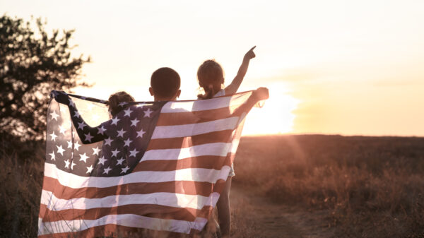 A happy family with an American flag at sunset.