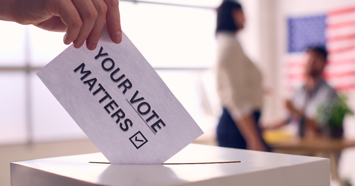 A hand putting a piece of paper in a ballot box with the words "your vote matters"