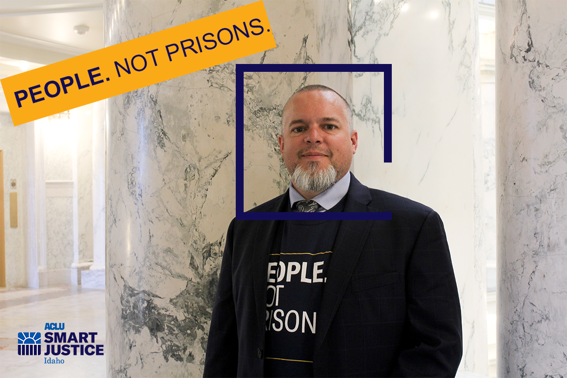 Jason is a tanned middle aged man with a salt and pepper beard, looking pleasantly at the camera from inside the marble rotunda in the Idaho State Capitol Building.