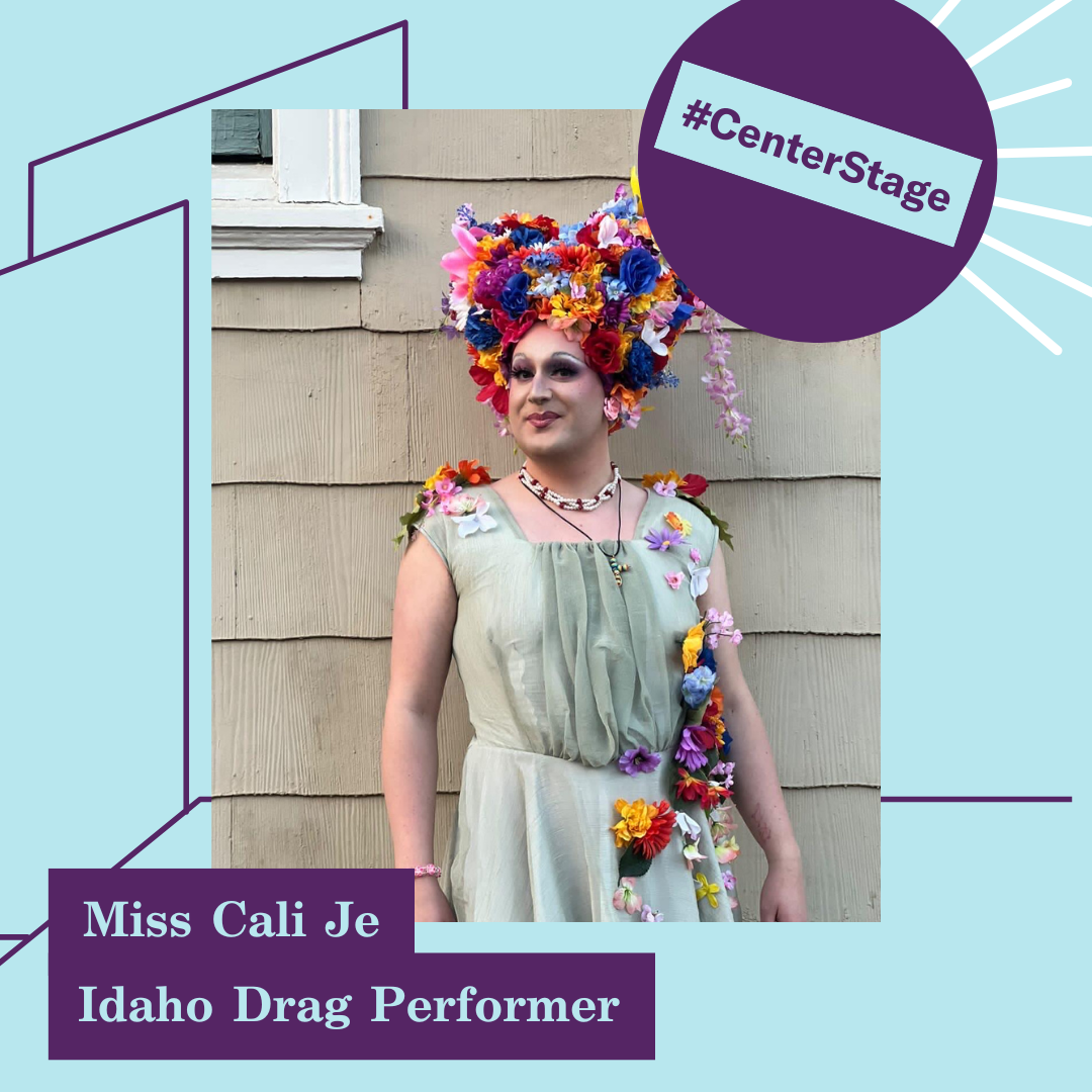 Miss Cali Je is centered in the image, wearing a full drag get-up complete with a hairstyle of flowers. She is standing in front of a beige wall, and the image is encompassed within a purple and blue background with the label #centerstage