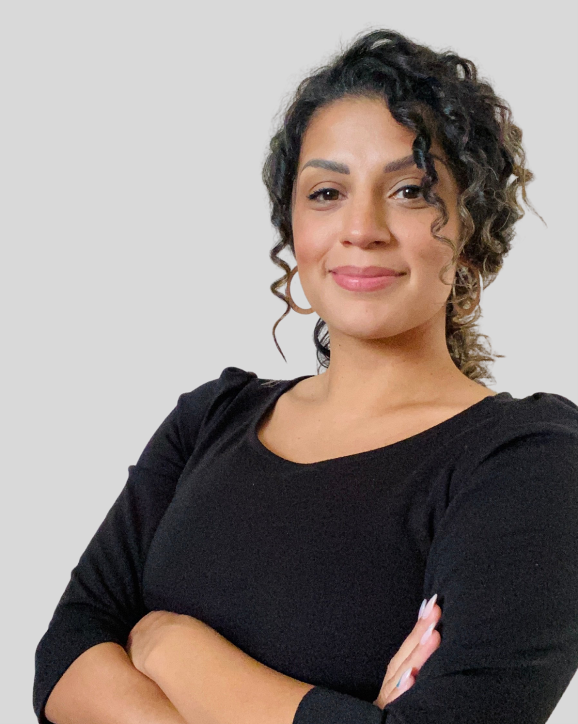 A picture of Chandra with her arms crossed, smiling confidently at the camera.