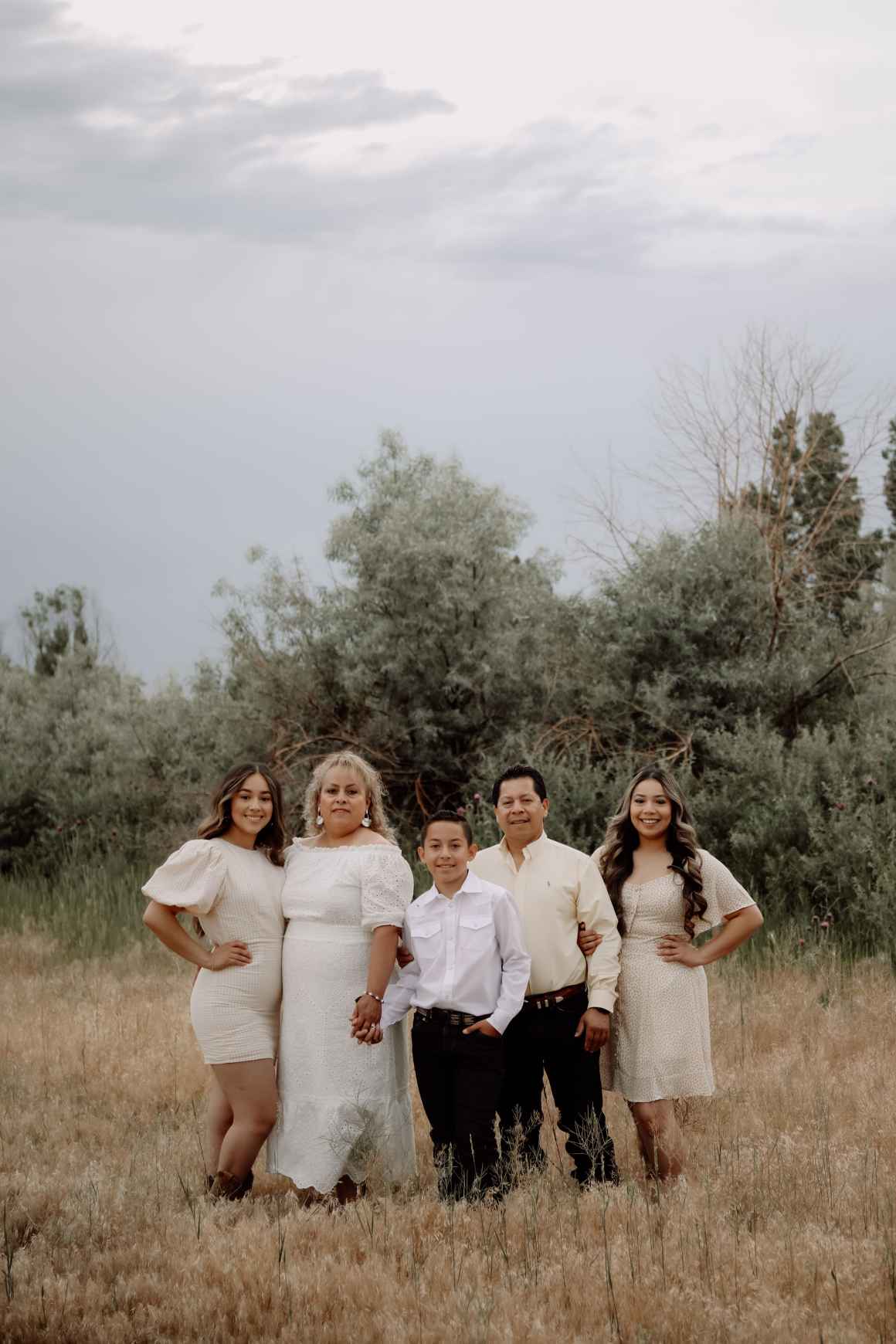 A photo of Natalie and her family, outside with trees in the background.