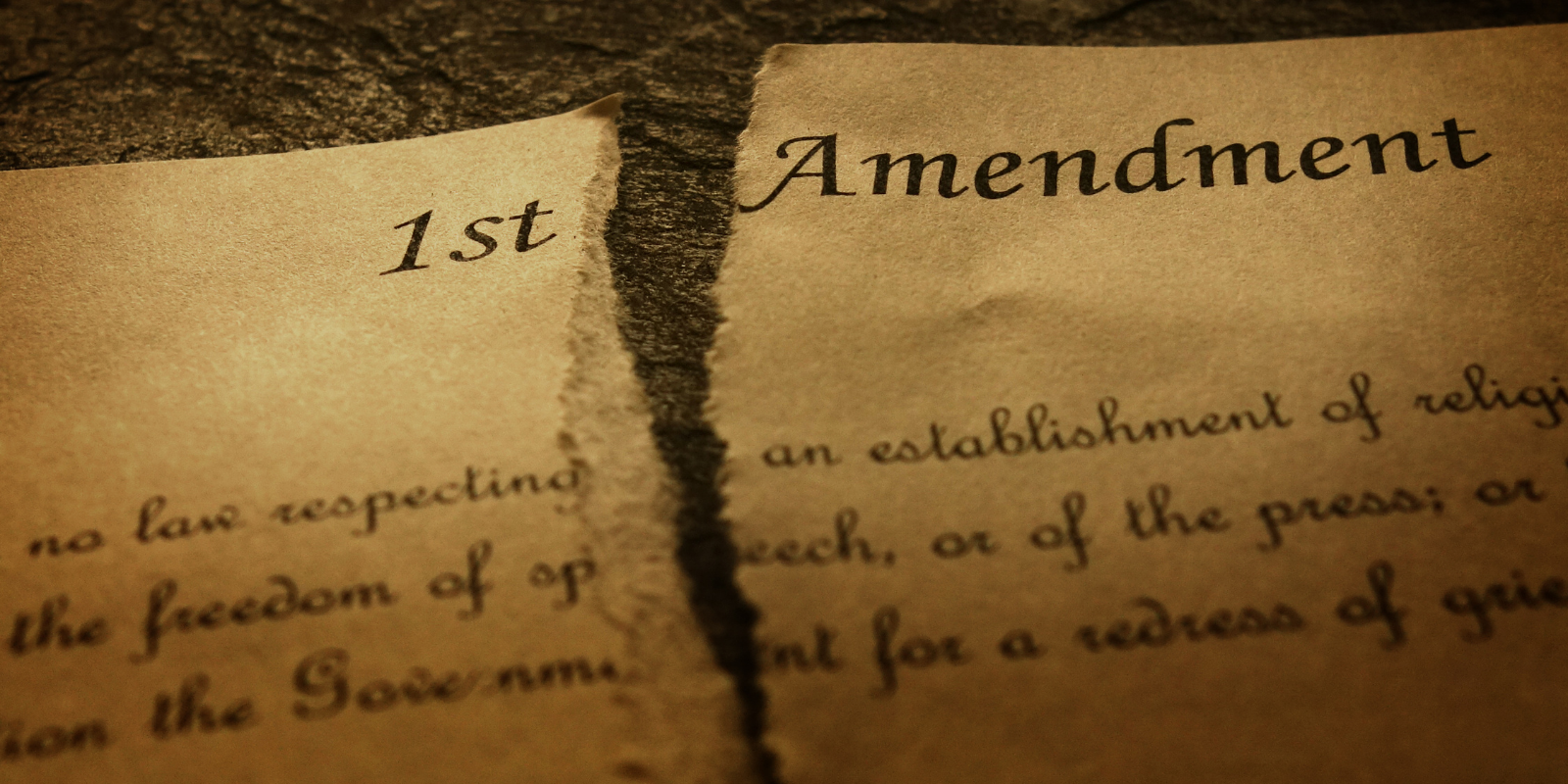 An aging document with the First Amendment is torn in half