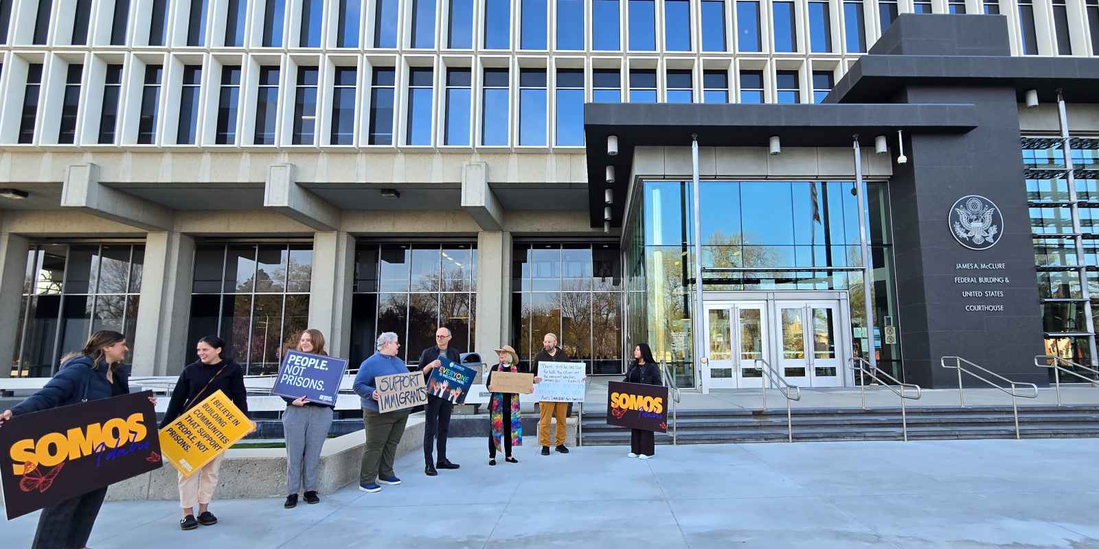 A group of eight advocates hold signs in support of immigrants standing in front of the federal court building in boise, idaho.