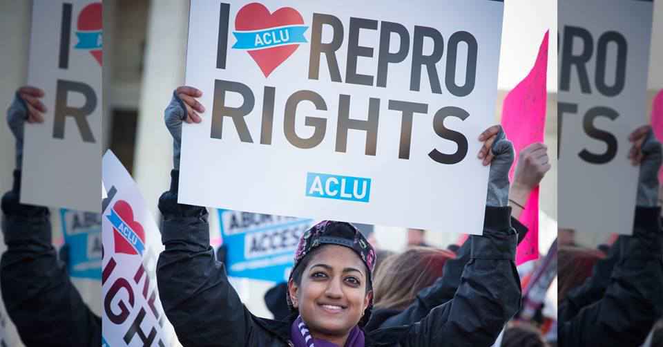 Person holding protest sign that says I (heart) REPRO RIGHTS and ACLU logo