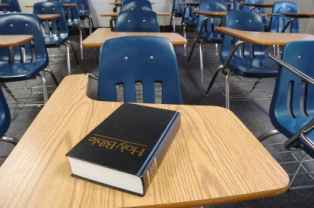 a classroom full of desks and chairs with a holy bible on one desk