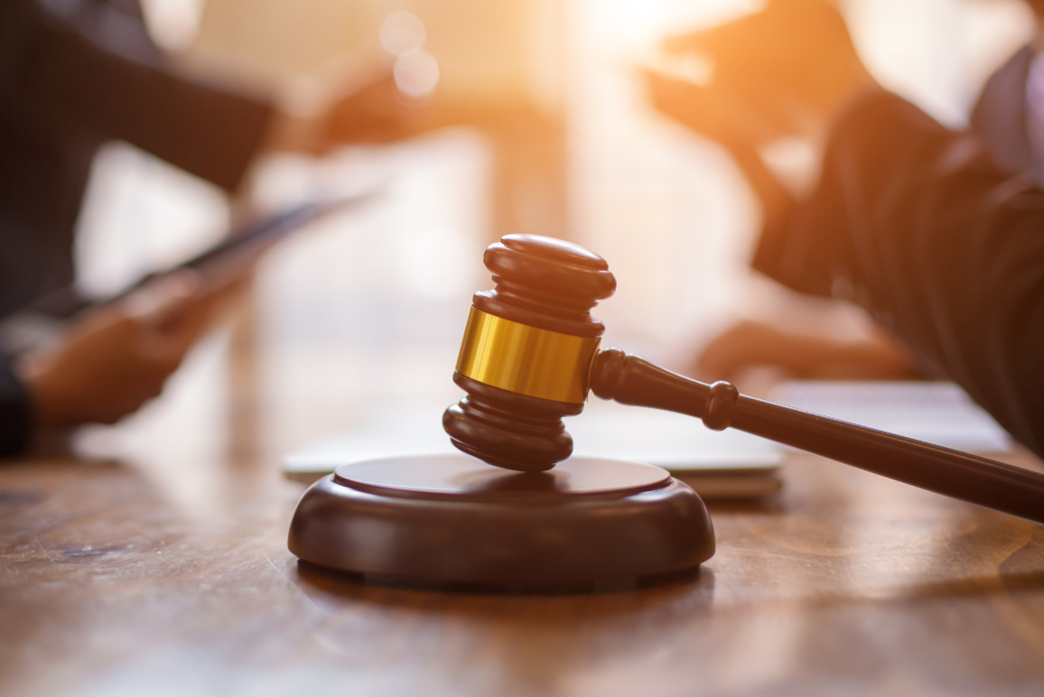 A judge's gavel with lawyers talking in the background