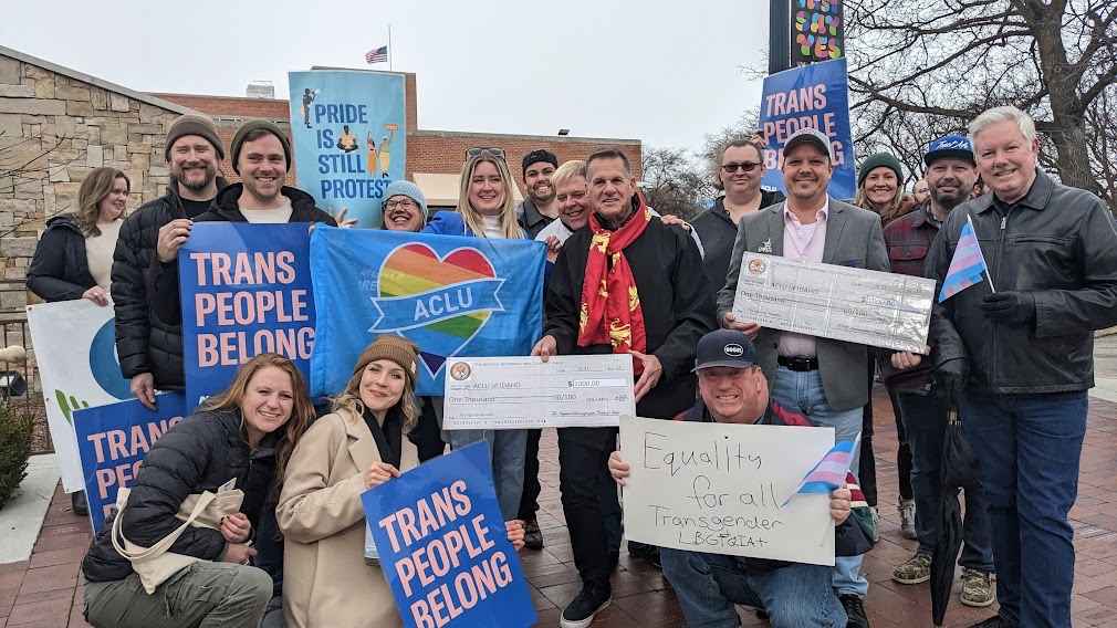 A group of people holding signs that read "trans people belong" 