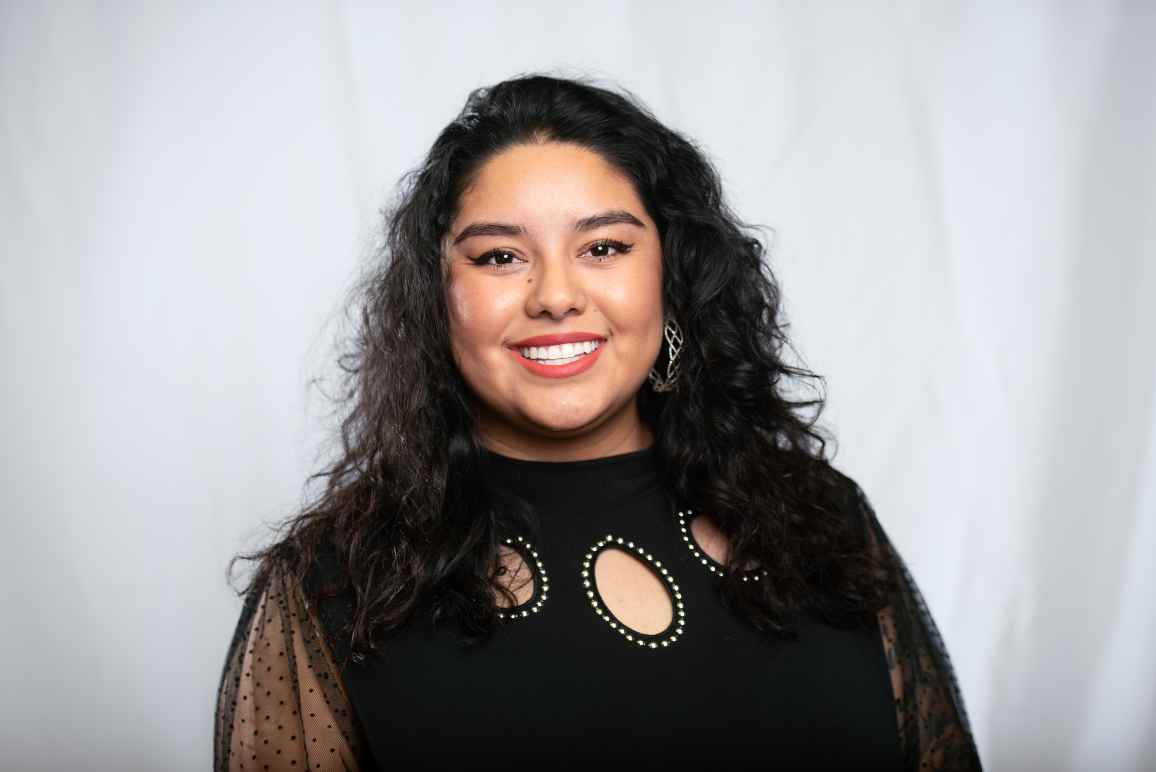 Rosseli is centered in front of a white cloth background.