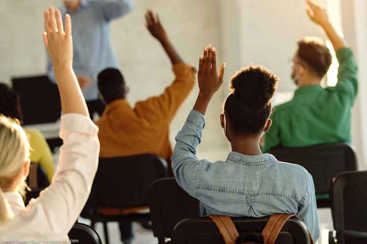 Students raising their hands in a classroom.