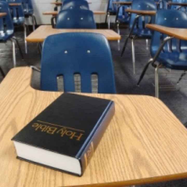 Bible in schools a classroom full of desks and chairs with a holy bible on one desk