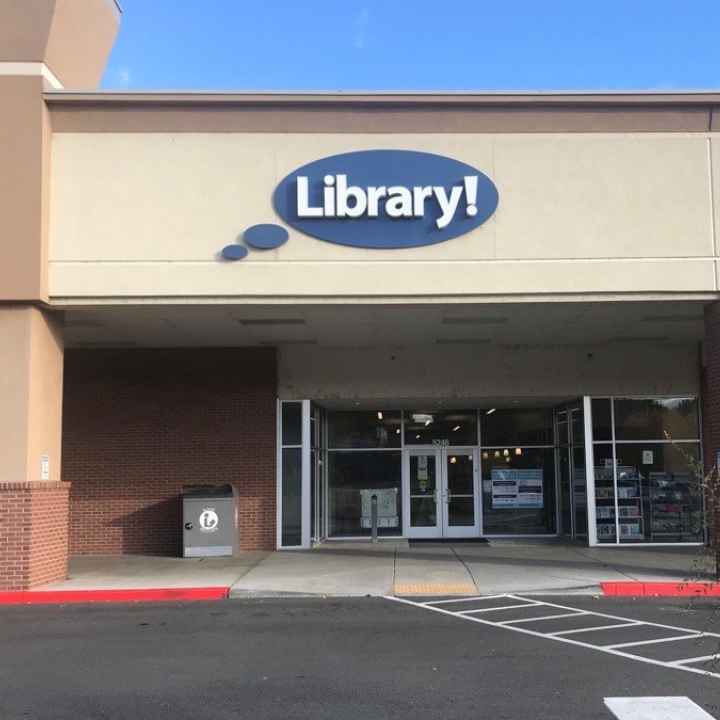A picture of the Hillcrest Library in Boise. A light brown building with a blue circular sign that says "Library!"
