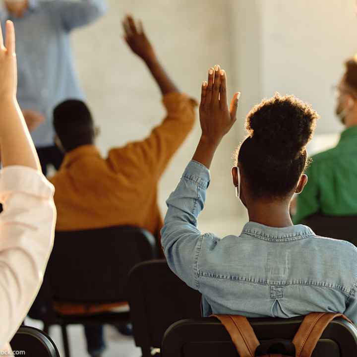 Students raising their hands in a classroom.